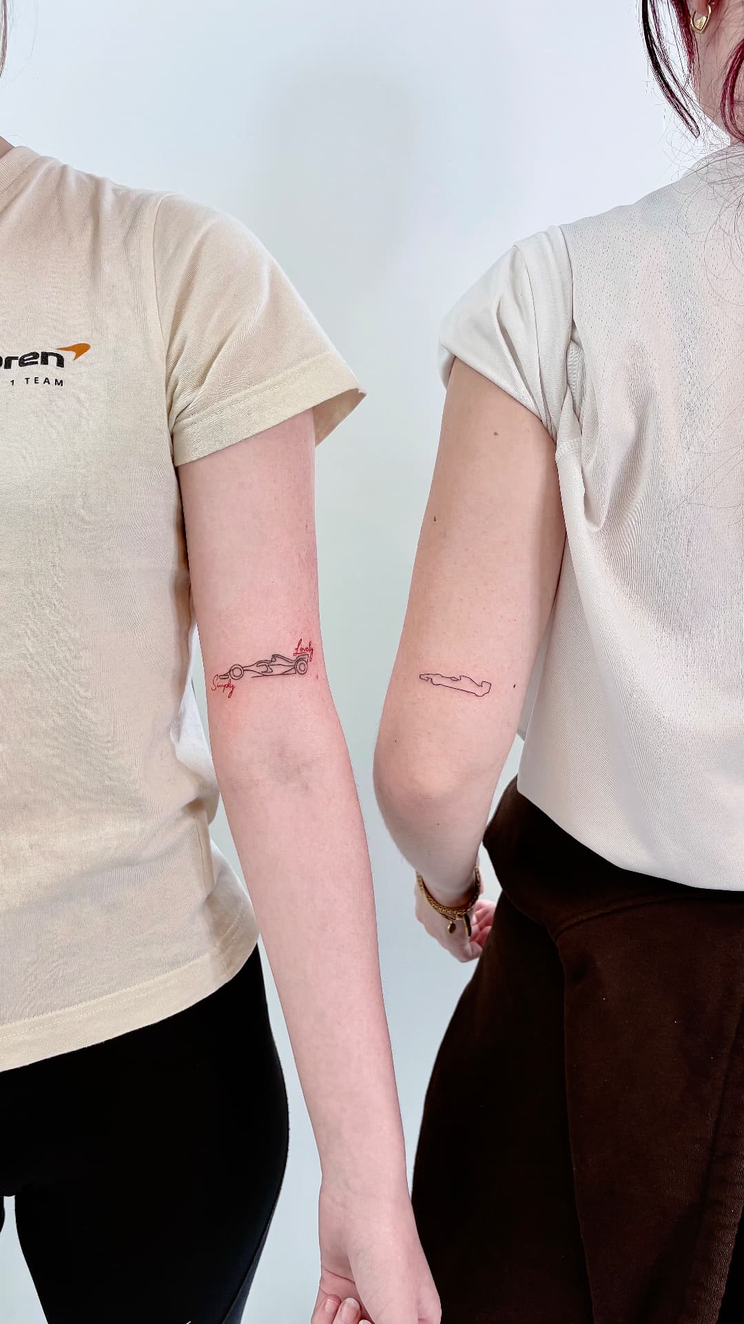 Fine line racing car outlines tattooed on the back of an upper arm