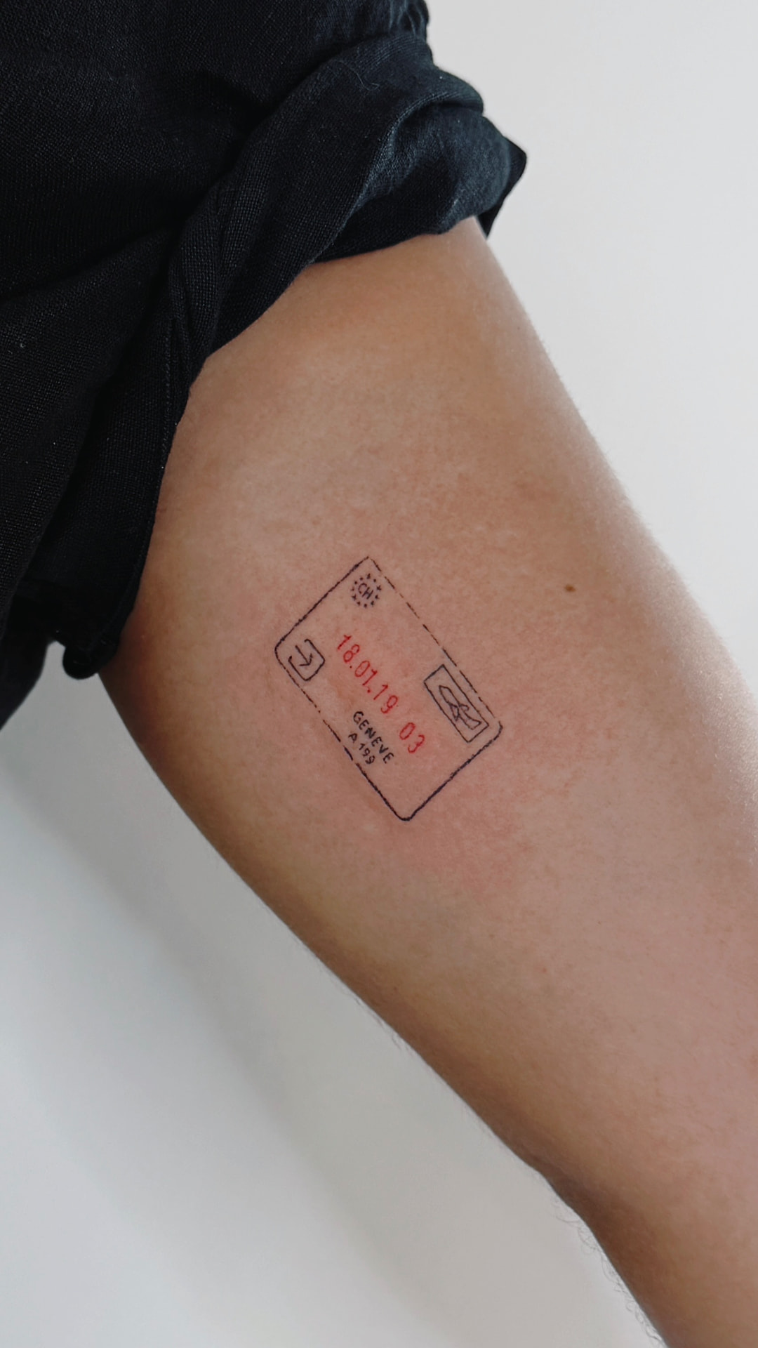 Fine line airport entry stamp tattoo on an upper arm